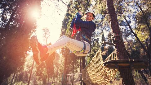 Mädchen fliegt mit einer Zipline durch den Wald | © iStock-649306990_jovanmandic