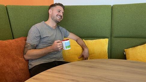 Maurice in der Cafeteria mit Tasse in der Hand