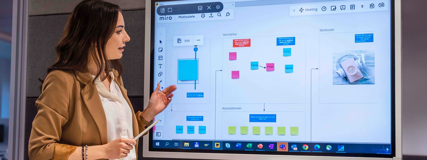 Mitarbeiterin präsentiert Inhalte auf einem digitalen Whiteboard