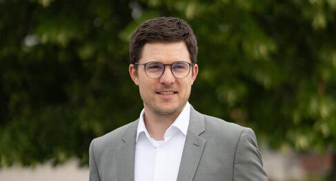 Porträt einer Person im Business‑Kontext vor grünem Hintergrund